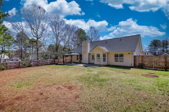 rear view of house with a lawn, a fenced backyard, a gazebo, a chimney, and a patio area