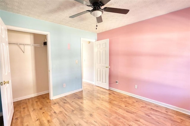 unfurnished bedroom featuring wood finished floors, baseboards, ceiling fan, a closet, and a textured ceiling