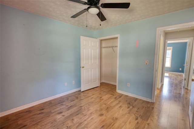 unfurnished bedroom with baseboards, a textured ceiling, wood finished floors, and a ceiling fan