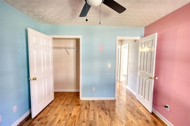 unfurnished bedroom with a textured ceiling, wood finished floors, a closet, baseboards, and ceiling fan