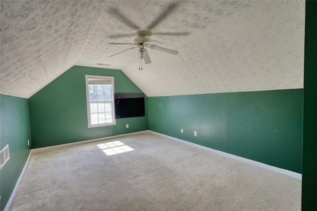 additional living space with baseboards, carpet, lofted ceiling, a textured ceiling, and a ceiling fan