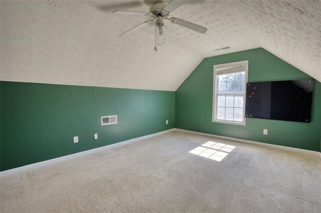 additional living space with visible vents, carpet floors, and a textured ceiling