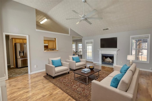 living room with a fireplace with flush hearth, light wood-type flooring, a wealth of natural light, and a textured ceiling