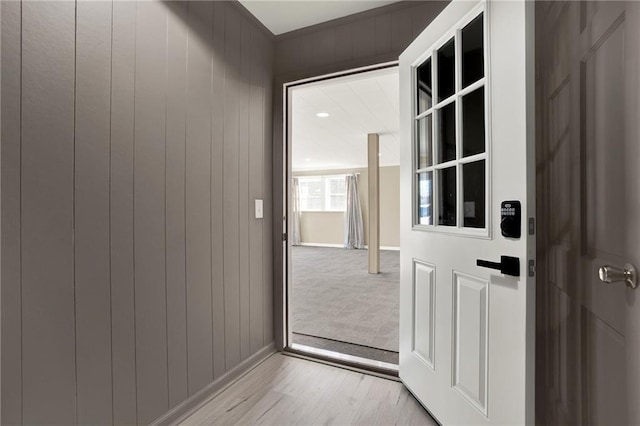 doorway featuring light hardwood / wood-style flooring and wood walls