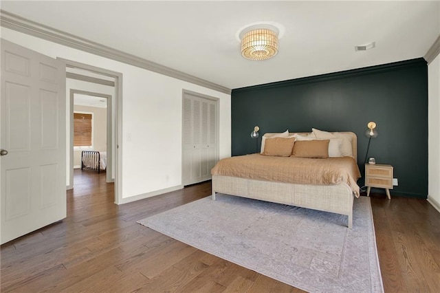 bedroom with a closet, dark hardwood / wood-style flooring, and ornamental molding