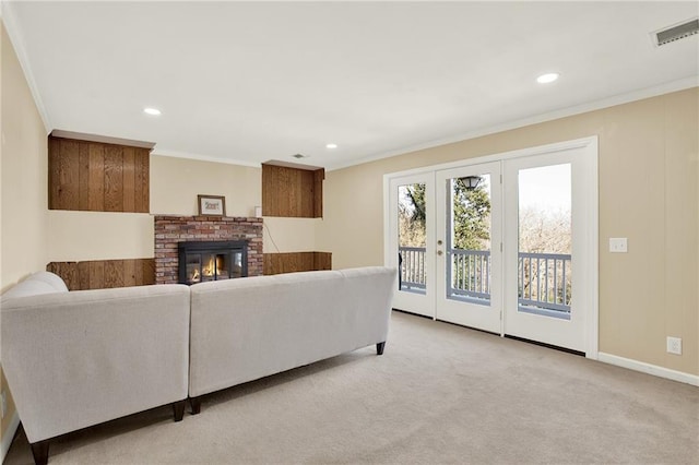 living room with a brick fireplace, ornamental molding, and light colored carpet