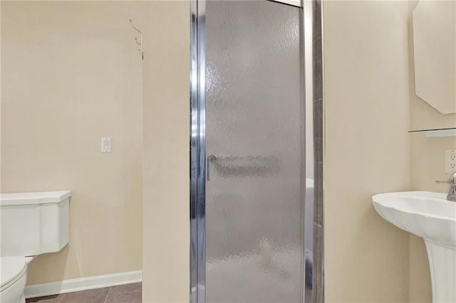 bathroom featuring toilet, tile patterned flooring, a shower with door, and sink