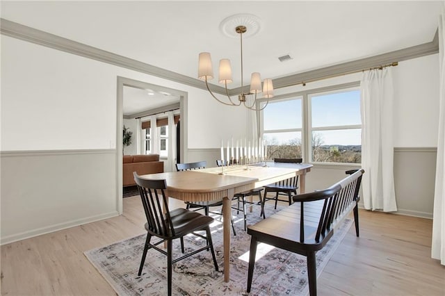 dining room with crown molding, a chandelier, and light hardwood / wood-style flooring