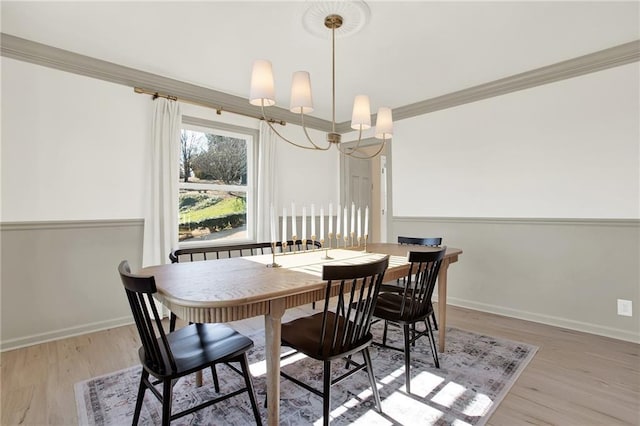 dining room with an inviting chandelier, ornamental molding, and light hardwood / wood-style floors