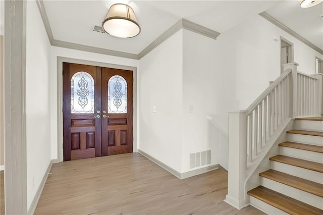 entrance foyer with crown molding, light hardwood / wood-style floors, and french doors