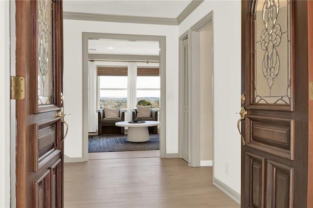 foyer entrance with crown molding and light hardwood / wood-style flooring