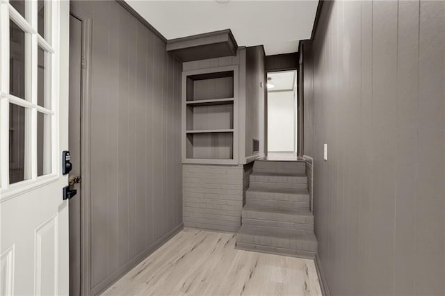 interior space with hardwood / wood-style flooring, built in shelves, and wooden walls