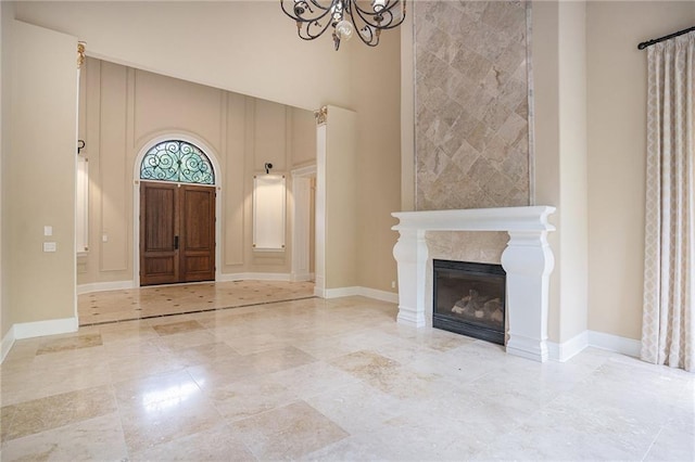 foyer entrance with a notable chandelier, a premium fireplace, and a towering ceiling