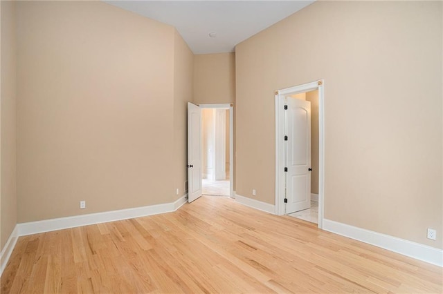 unfurnished room featuring a towering ceiling and light hardwood / wood-style flooring