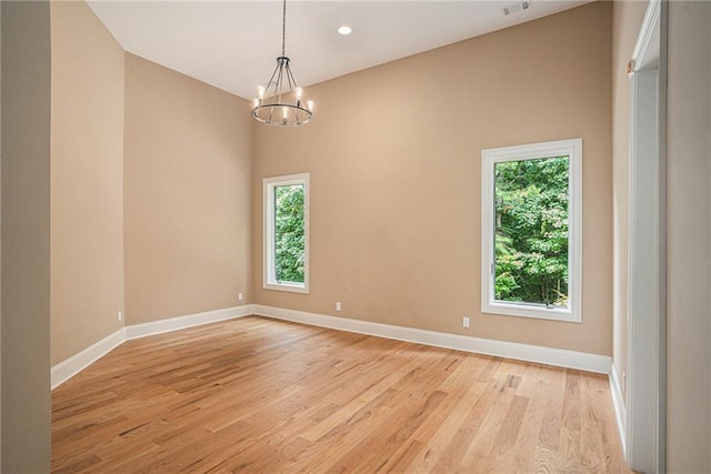 unfurnished room with light hardwood / wood-style floors and a chandelier