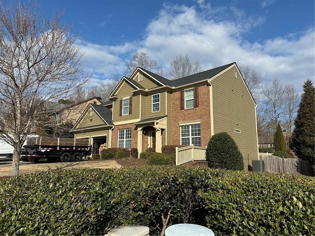 view of front of home with concrete driveway, brick siding, and fence