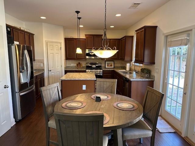 kitchen with stainless steel appliances, visible vents, hanging light fixtures, a kitchen island, and a sink