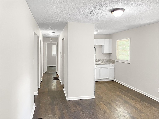 hall with dark wood-type flooring and a textured ceiling