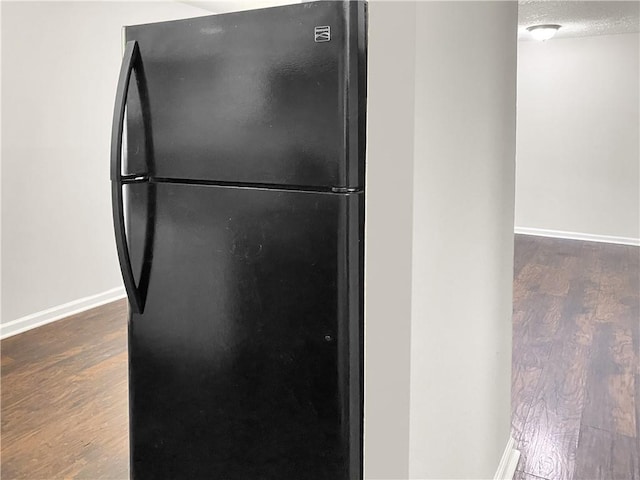 kitchen featuring black refrigerator, dark wood-type flooring, and a textured ceiling