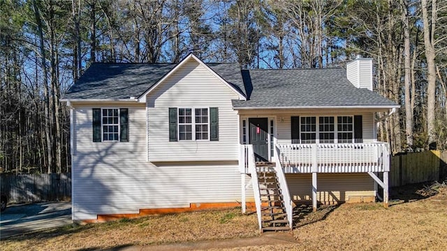 view of front of home with a shingled roof, fence, a chimney, and stairs