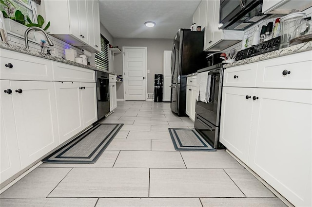 kitchen with light stone countertops, black appliances, and white cabinetry