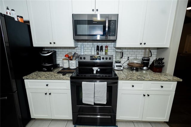 kitchen featuring light stone counters, white cabinets, backsplash, and black appliances