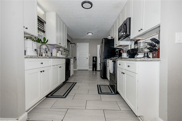 kitchen featuring black appliances, light stone counters, and white cabinetry