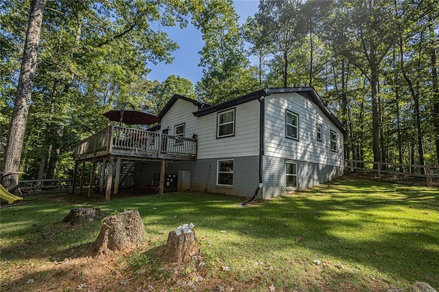 rear view of property with a wooden deck and a lawn