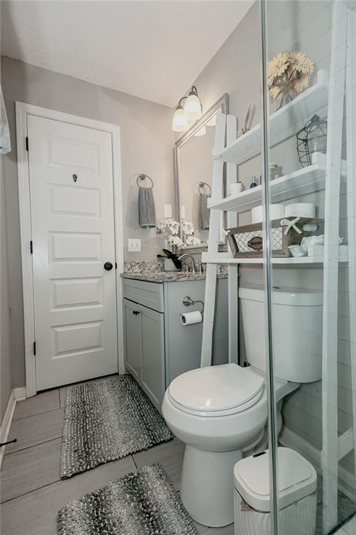 bathroom with vanity, a shower with shower door, and toilet