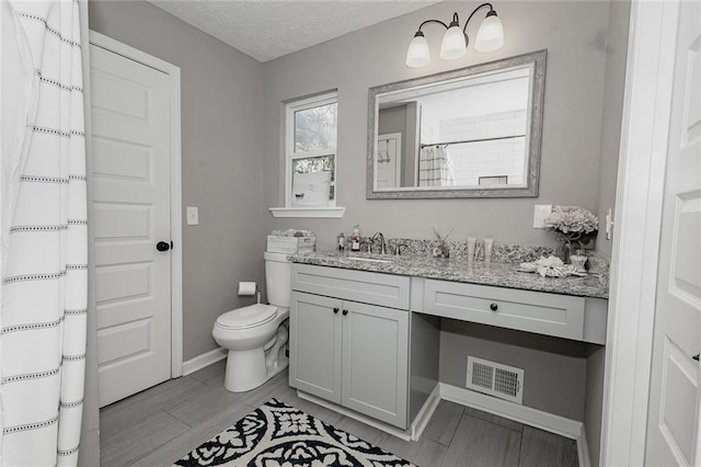 bathroom featuring vanity, toilet, and a textured ceiling