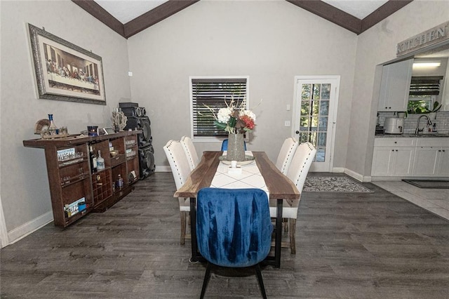 dining area with sink, dark hardwood / wood-style floors, beam ceiling, and high vaulted ceiling