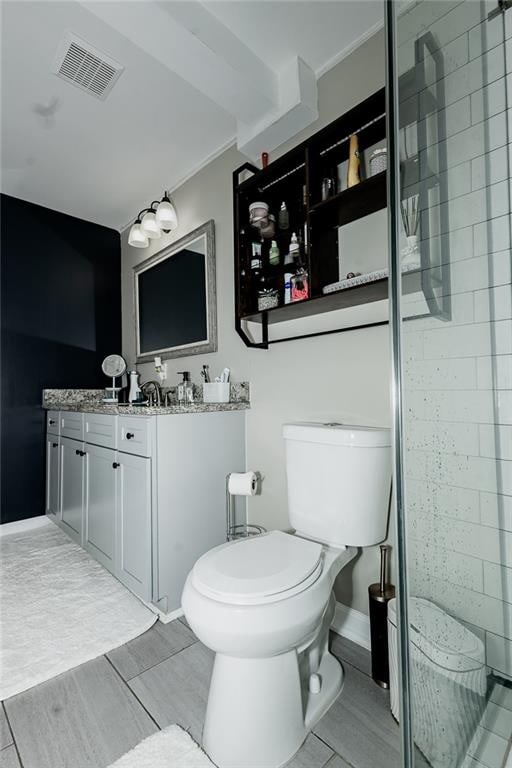 bathroom with tiled shower, tile patterned floors, vanity, and toilet