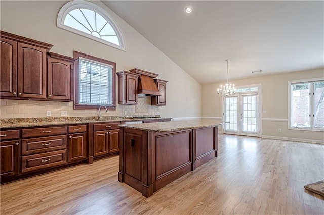 10280 Medridge Cir, Johns Creek, GA 30022 - kitchen featuring custom exhaust hood, high vaulted ceiling, light wood-style floors, a kitchen island, and a chandelier