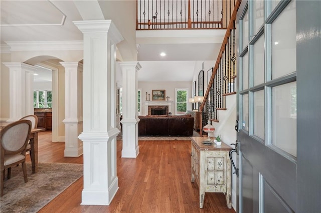 entryway with decorative columns, crown molding, hardwood / wood-style floors, and high vaulted ceiling