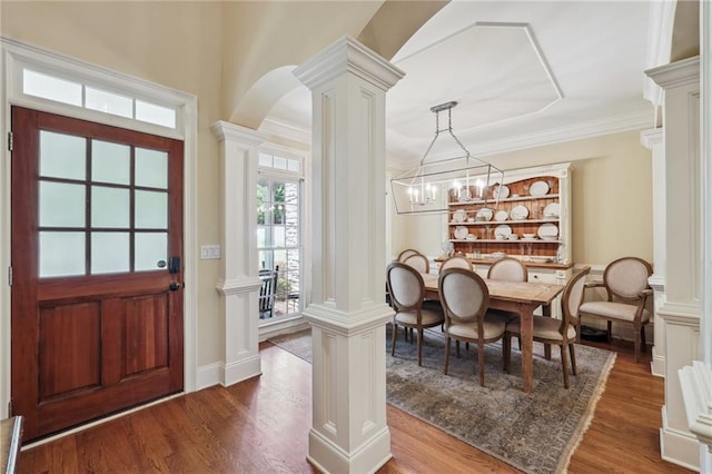 foyer featuring decorative columns, wood-type flooring, and ornamental molding