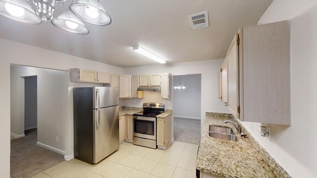 kitchen featuring appliances with stainless steel finishes, a sink, under cabinet range hood, light colored carpet, and baseboards