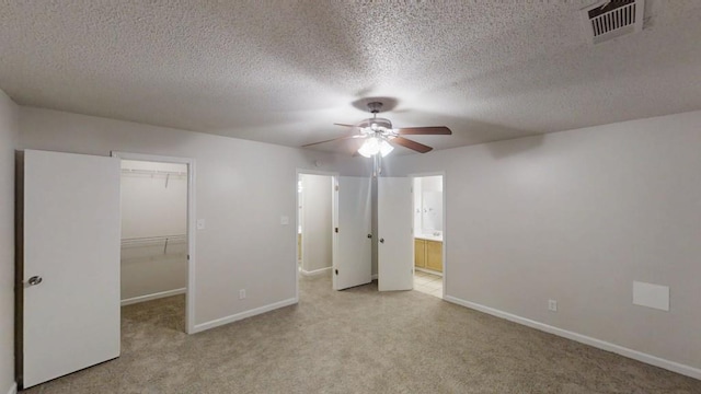 unfurnished bedroom with a spacious closet, carpet floors, baseboards, a closet, and a textured ceiling