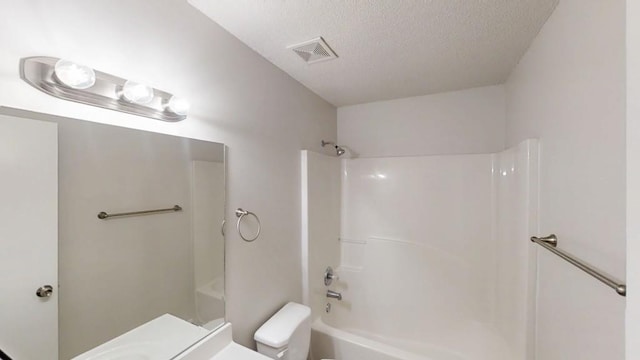 bathroom with a textured ceiling, toilet, and tub / shower combination