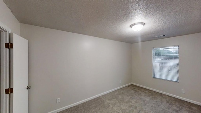 empty room with carpet flooring, a textured ceiling, and baseboards