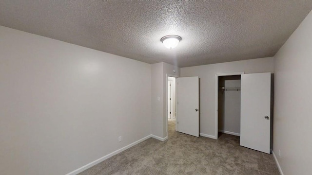 unfurnished bedroom featuring carpet, a textured ceiling, baseboards, and a closet