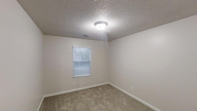 carpeted empty room with a textured ceiling and baseboards