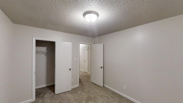 unfurnished bedroom featuring carpet, a textured ceiling, baseboards, and a closet