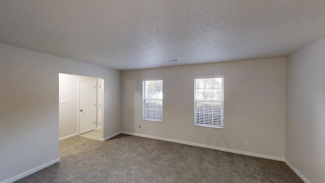 carpeted empty room featuring baseboards and a textured ceiling