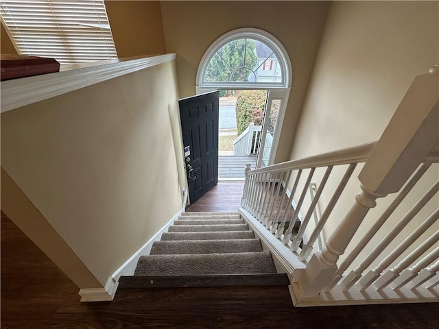 stairs featuring a high ceiling, baseboards, and wood finished floors