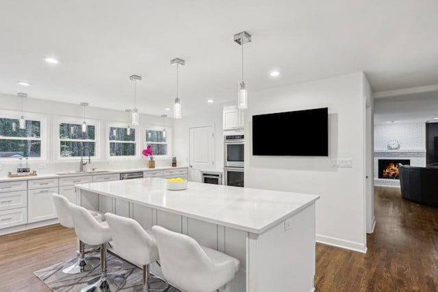 kitchen with a breakfast bar, sink, hanging light fixtures, a kitchen island, and white cabinets