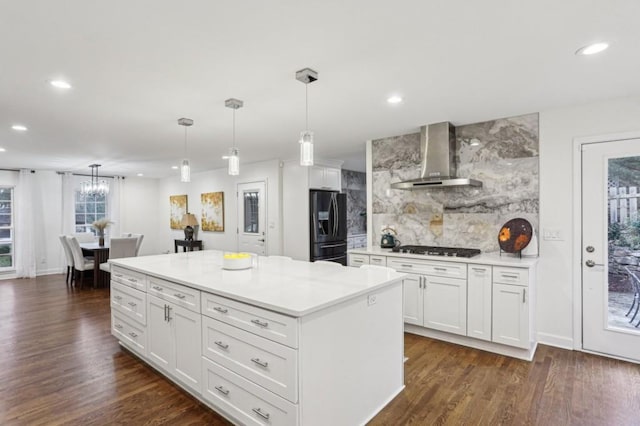 kitchen with white cabinetry, black fridge with ice dispenser, pendant lighting, and wall chimney exhaust hood