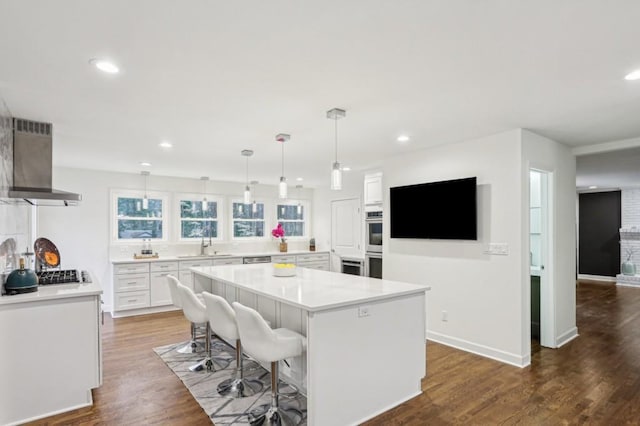 kitchen featuring white cabinetry, a center island, island range hood, and a breakfast bar