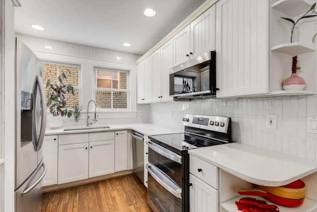 kitchen featuring sink, appliances with stainless steel finishes, white cabinets, light hardwood / wood-style floors, and backsplash