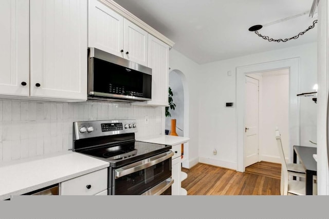 kitchen featuring backsplash, stainless steel appliances, light hardwood / wood-style floors, and white cabinets