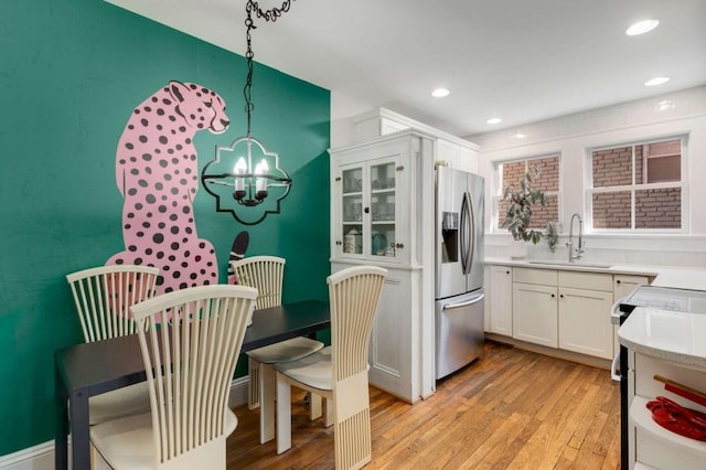 kitchen with pendant lighting, stainless steel fridge with ice dispenser, sink, and white cabinets